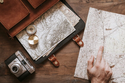 Top 10 Travelgoals 2024 - World map hand shows something on this map. A compass and a travel bag are also included