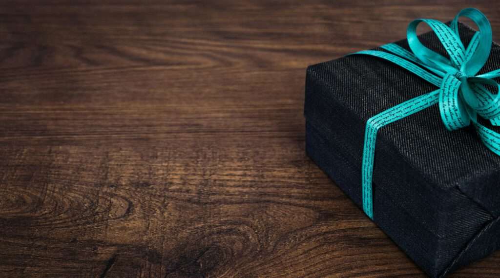 Top 10 Tips work and travel - Wooden base with a black gift and turquoise ribbon